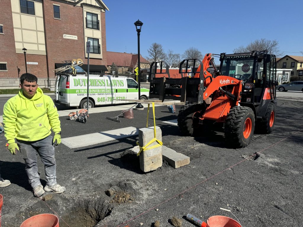 Dutchess Lawns & Masonry crew member working alongside a telehandler at a job site