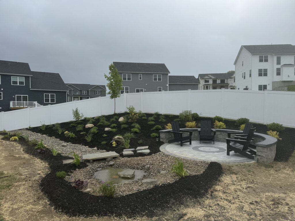 Stone firepit seating area with landscape plantings