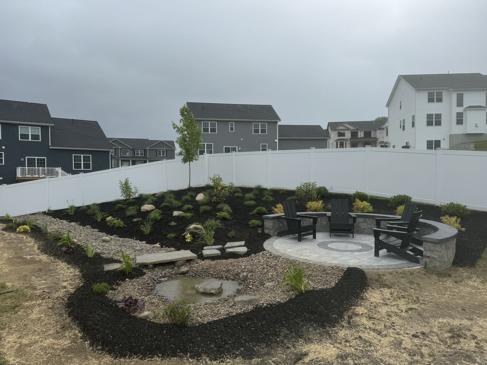 Stone firepit seating area with retaining wall and landscape design